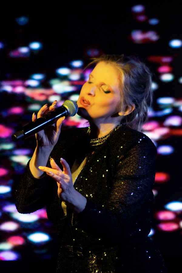 Professional picture of our female singer in Argentina passionately singing into microphone while bright LED lights shine around her | Altus Entertainment